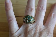 This ring is gold plated over sterling silver and is set with numerous small emeralds in a domed style setting. The stones are lower commercial quality emeralds and are somewhat opaque but still have nice green color. Condition is good with general light wear from age and light tarnish, if polished the ring would have a bright gold finish.  Item is sold as-is. We welcome haggling in this shop! Unique Hallmarked Yellow Gold Emerald Ring, Unique Green Emerald 14k Gold Ring, Vintage Hallmarked Emerald Jewelry, Unique Hallmarked Emerald Ring, Unique Green Emerald Ring In 14k Gold, Unique 14k Gold Green Emerald Ring, Unique 14k Gold Emerald Ring, Antique 14k Gold Green Emerald Ring, Antique Green Emerald Ring In 14k Gold