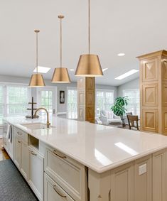 a large kitchen with an island in the middle and three lights hanging from the ceiling