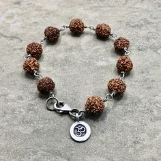 "Lovely Rudraksha Seed Beads wrapped in oxidized sterling silver with a Hilltribe fine silver OM charm. This beaut is 7 1/4\" and closes securely with a sterling silver lobster clasp. Rudraksha is worn at all times or kept close to the skin, it is a sacred seed that emits a potent protective energy, enabling the wearer to achieve their greater potential." Spiritual Silver Beaded Bracelets, Spiritual Bracelet With Oxidized Finish As Gift, Spiritual Sterling Silver Beaded Bracelets, Spiritual Sterling Silver Bracelets, Spiritual Silver Hand-strung Rosary Bracelet, Sterling Silver Spiritual Bracelet For Meditation, Spiritual Sterling Silver Bracelets With Silver Clasp, Nickel-free Spiritual Beaded Bracelets For Healing, Nickel Free Spiritual Beaded Bracelets For Healing