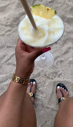 a woman is holding up a drink in her hand with a straw and pineapple on top