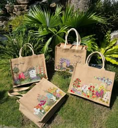 three bags with flowers on them sitting in the grass next to some trees and plants