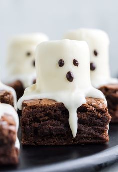 chocolate brownies with marshmallows and white icing on top are sitting on a black plate