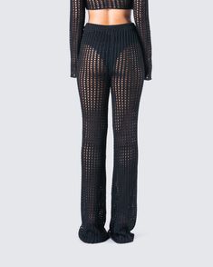 the back view of a woman wearing black sheer knit pants and crop top