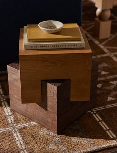 a wooden table with a bowl on top of it next to a chair and rug