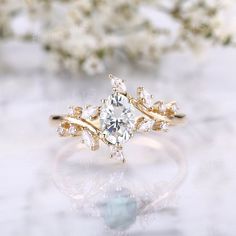 a diamond ring sitting on top of a table next to some white and green flowers