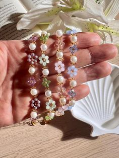 a person is holding some pearls and flowers in their hand while they are sitting on a table