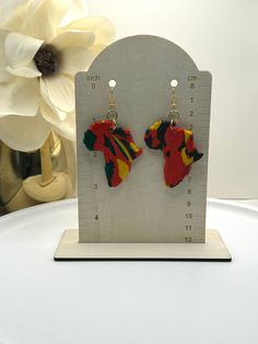 These lightweight Africa-shaped dangles are perfect for celebrating the culture. They feature a bold design for a stylish addition to any outfit. Show your pride with these beautiful earrings! · Length: 3" · Handmade Polymer Clay Earrings · Lightweight · Nickel Free Post or hook · Each item is handmade; therefore, items will have slight variations. No two pair will be alike. · To clean your earrings, please wipe with a damp cloth. · Perfect gifts for you, friends, or family. Trendy Multicolor Dangle Plug Earrings, Trendy Red Dangle Hoop Earrings, Trendy Multicolor Drop Plug Earrings, Trendy Handmade Red Earrings, Red Dangle Plug Earrings With Ear Wire, Africa Earrings, Free Post, Bold Design, Handmade Polymer Clay