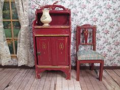 a doll house with a red cabinet and chair