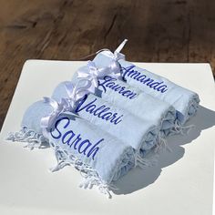 two towels with names on them sitting on top of a white plate and wooden table