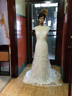 a mannequin wearing a wedding dress in front of an open door