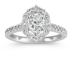 a white gold ring with an oval cut diamond in the center and pave set shoulders