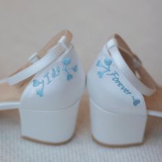 a pair of white shoes with blue flowers painted on the bottom and heel are shown