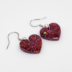 Sparkling red glitter heart earrings featuring crystal clear epoxy resin and True Red fine glitter with a hint of Deep Purple glitter and Holographic glitter shards.  Finished with Stainless Steel ear wires with soft silicone backs.  Epoxy coated on the both sides for extra protection and shine.  Romantic heart earrings measure 1 1/4 inches long and 3/4 inch wide and are very lightweight.  These earrings make the perfect gift for wife and gift for girlfriend, and of course a brilliant gift for you.  Why not treat yourself?     ⭐ CARE   Wipe clean with a soft cloth (such as an eyeglass cleaning cloth).  Do not use alcohol or acetone as this will damage the glossy surface.  It is not recommended to wear in water.  Do not expose to extreme heat.  To extend the life of your resin pieces, store Valentine's Day Party Resin Earrings, Cheap Red Resin Earrings, Heart-shaped Glitter Earrings For Gifts, Heart-shaped Crystal Rhinestone Earrings For Valentine's Day, Handmade Heart-shaped Resin Earrings, Cheap Heart-shaped Resin Earrings, Crystal Clear Epoxy Resin, Red Heart Earrings, Clear Epoxy Resin