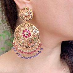 Featuring a pair of beautiful multicoloured jadau chandbali earrings in gold plated silver. The setting stones are freshwater pearls and ruby, emerald, sapphire look alike synthetic, but high quality stones. The hanging beads are real ruby, blue sapphires and freshwater pearls. The earrings come with a bombay screw and a french clip and weigh about 35gms