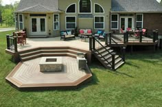 a patio with steps, seating and fire pit in front of a house on the grass