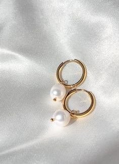 The Elora earrings are small hoop earrings adorned with a fresh water pearl. Simple and elegant, making them the perfect pair for a casual day out or a dressed up look. - Composed of - Stainless steel 18k gold plating Fresh water pearls tarnish free & hypoallergenic Everyday Pearl Charm Huggie Earrings, Small Hoop Pearl Earrings In Yellow Gold, Classic Gold Hoop Earrings With Pearl Charm, Teardrop Hoop Earrings With Pearl Charm, Gold Plated, Small Hoop Yellow Gold Pearl Earrings, Everyday 14k Gold Filled Pearl Pendant Earrings, Yellow Gold Pearl Small Hoop Earrings, Classic Gold-plated Hoop Earrings With Pearl Drop, Classic Gold Plated Hoop Earrings With Pearl Drop