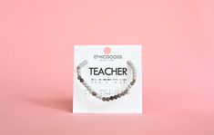 the teacher bracelet is on display in front of a pink background with white and black beads