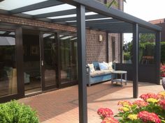 a patio covered in furniture and flowers next to a brick building with sliding glass doors