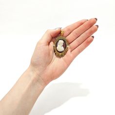 A fine antique Victorian convertible brooch / pendant for a necklace.  In 14k gold.  Comprising a cameo brooch with a oval reserve for a photo to the reverse and a tapered bail.   Centered on a pink and white carved agate or hard stone cameo of a beautiful young woman with flowing curly hair, earrings, and a ruffled dress.   The sides are set with small, round pearls and there is applied twisted rope and granulated decoration throughout.  Simply a wonderful piece of Victorian jewelry!  (Chain fo Victorian Pendant Brooches With Cabochon, Collectible Cameo Pendant Brooches, Antique Oval Necklace With Brooch, Formal Cameo Pendant Brooch, Gold Cameo Medallion Brooch, Gold Cameo Medallion Brooches, Elegant Locket Brooches For Gift, Antique Cameo Brooches As Gift, Antique Cameo Brooches For Gift