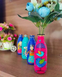 three colorful vases with flowers in them sitting on a table next to other decorative items