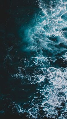 an aerial view of the ocean with dark blue water and white foamy waves in the foreground