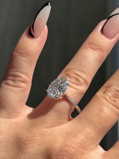 a woman's hand with an oval shaped diamond ring on top of her finger