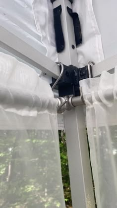 an open window with white curtains and black hardware on the bottom curtain is visible from outside