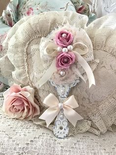 two pink roses are on top of an old lace doily with pearls and bows