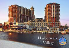 two tall buildings sitting next to each other on top of a body of water with boats in front of them