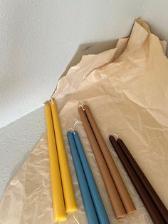 four different colored candles sitting on top of a piece of paper next to each other