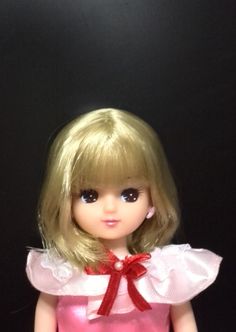 a doll with blonde hair wearing a pink dress and red bow on it's head