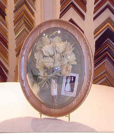 a vase filled with white flowers sitting on top of a table next to framed pictures