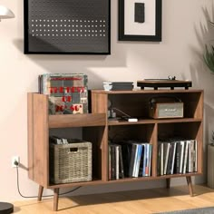 a book shelf with books and other items on it in a room next to a plant