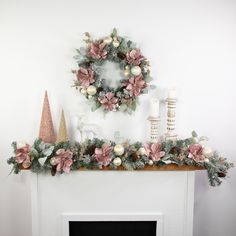 a fireplace mantel decorated for christmas with pink and white flowers, greenery and candles