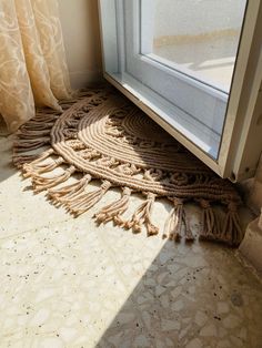 the sun shines through an open window onto a roped rug on the floor