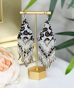 Elevate your accessory game with our Wild For You Tassel Earrings. Crafted from delicate seed beads, these earrings feature a captivating triangle design in a combination of elegant ivory and fierce leopard print. The addition of charming tassels made from seed beads adds a touch of movement and flair to these lightweight earrings.
The unique blend of patterns and textures makes these earrings a versatile choice for a range of outfits, from casual to dressy. Whether you're stepping out for a nig Beaded Bracelet Patterns, Triangle Design, Lightweight Earrings, Light Weight Earrings, Fringe Earrings, Tassel Earrings, Bracelet Patterns, Beaded Bracelet, Beaded Earrings