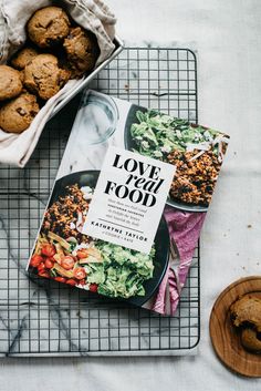 a cookbook sitting on top of a cooling rack next to some muffins