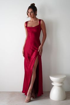 This gown is your perfect choice for debs, prom or any formal event. A look that blends classic glamour with contemporary style. Designed for timeless allure and effortless sophistication. Featuring a graceful cowl neckline and thick shoulder straps, this dress offers a flattering, structured fit. The sultry thigh-high slit adds a bold, modern touch, while the luxurious satin fabric drapes beautifully to enhance your silhouette. Highlights Stunning red gown with cowl neckline Soft satin material Red Fitted Floor-length Satin Dress, Red Fitted Backless Satin Dress, Red Fitted Satin Dress For Prom, Satin Maxi Dress With Lace-up Back For Prom, Red Fitted Satin Maxi Dress, Formal Satin Dress With Cowl Back, Fitted Satin Finish Evening Dress With Cowl Back, Fitted Floor-length Satin Dress With Back Opening, Satin Gown With Corset Back And Maxi Length