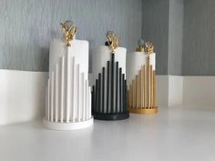 three white and gold vases sitting next to each other on top of a table