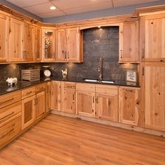 a large kitchen with wooden cabinets and black counter tops, along with wood flooring