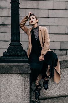 a woman sitting on top of a stone wall next to a lamp post