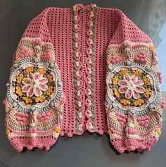 a pink crocheted sweater with flowers on it