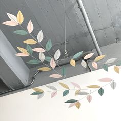 a wind chime hanging from the ceiling with leaves painted on it's sides