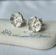 These little sterling silver flower earrings are handmade and lovely for everyday wear - a great addition to your jewellery collection or a gorgeous gift for her. Handcrafted from sterling silver, the flowers are then textured and shaped before being made into earrings and polished. A perfect all-rounder from your work meeting to a Lunch date to chilled evening with friends or family. Earrings measure approx 6mm diameter. A matching necklace is also available. Sterling Silver Flower Earrings, Stud Earrings Unique, Botanical Earrings, Daisy Studs, Silver Flower Earrings, Silver Earrings Handmade, Spring Jewelry, Daisy Earrings, Sterling Silver Flowers