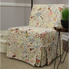 a living room with a chair covered in a flowered fabric and metal legs, next to a potted plant