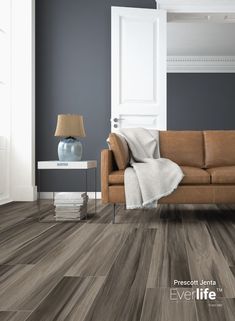 a living room with blue walls and wood flooring is pictured in this image, the couch has a throw blanket on it