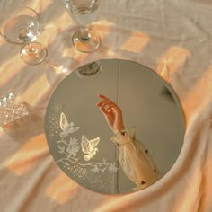 a person's hand is reflected in a mirror on a table with wine glasses