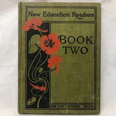 an old book with red flowers on the front and green cover that reads new education readers book two