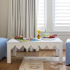 a white coffee table sitting on top of a wooden floor next to a blue chair