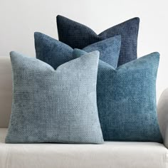 three pillows sitting on top of a white couch